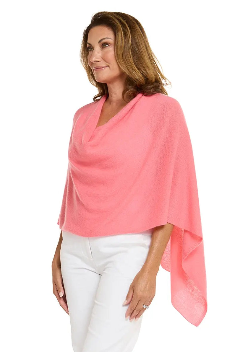 Woman wearing a coral poncho and white pants on a white background