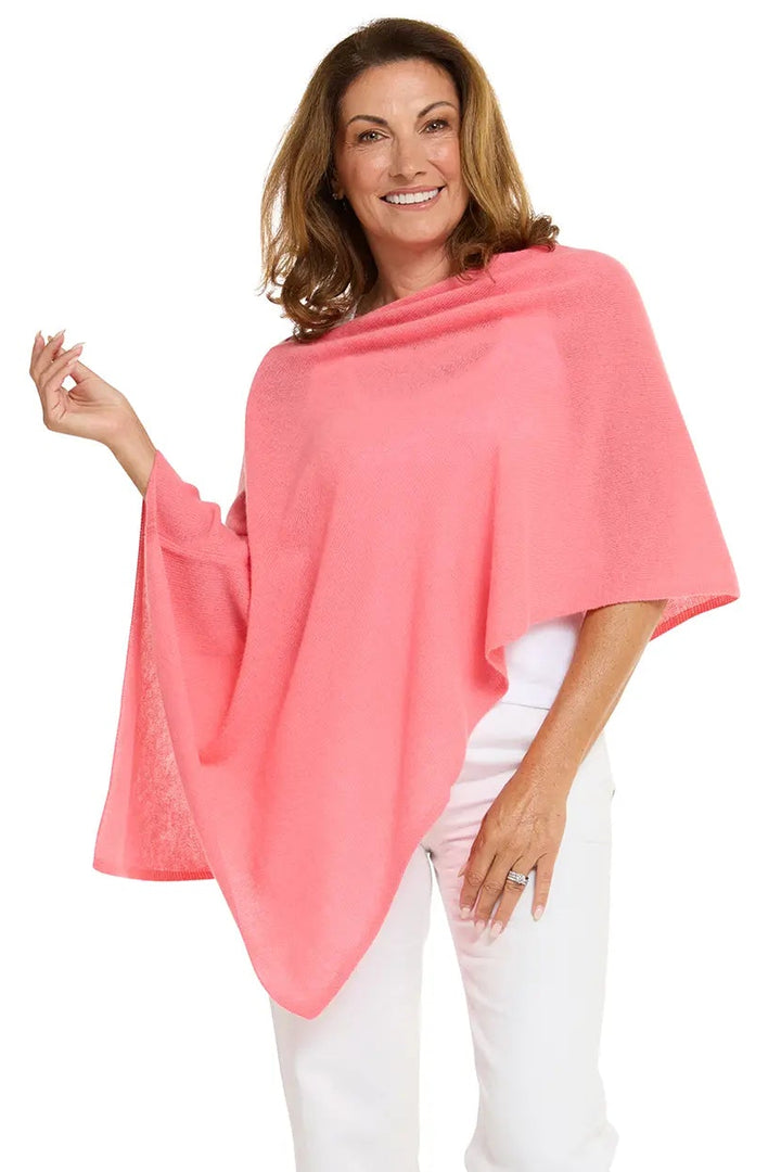 Woman wearing a pink poncho and white pants on a white background