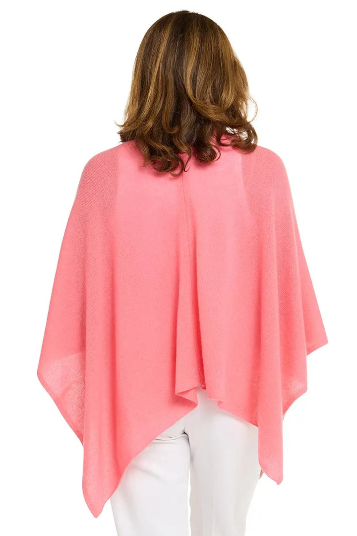 Woman wearing a pink poncho and white pants on a white background