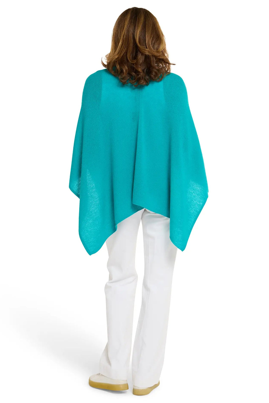 Person wearing a turquoise poncho and white pants on a white background