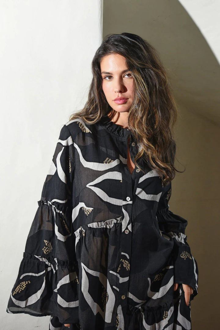 Woman wearing a black and white patterned dress against a neutral background