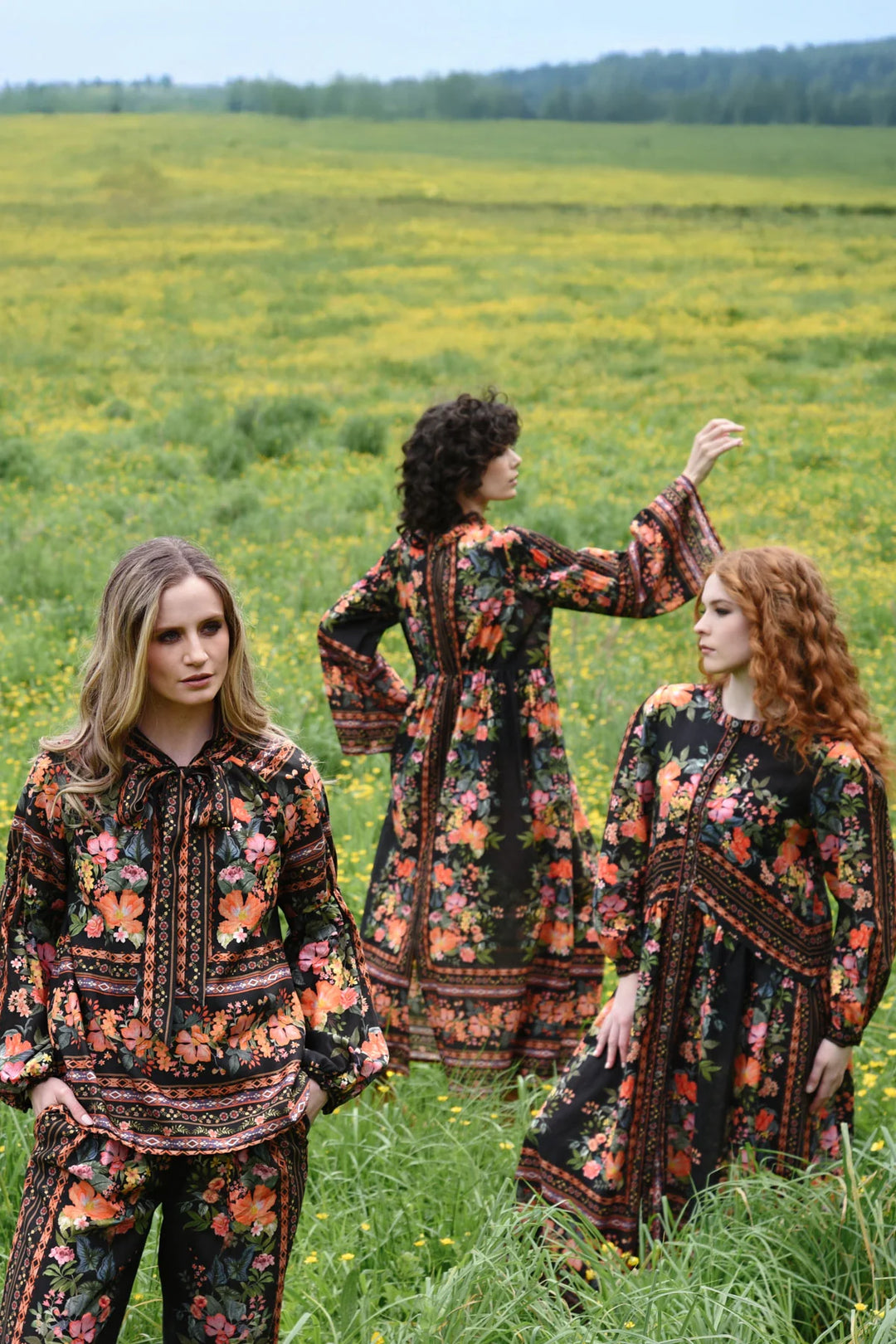 Three women in matching floral outfits standing in a field.