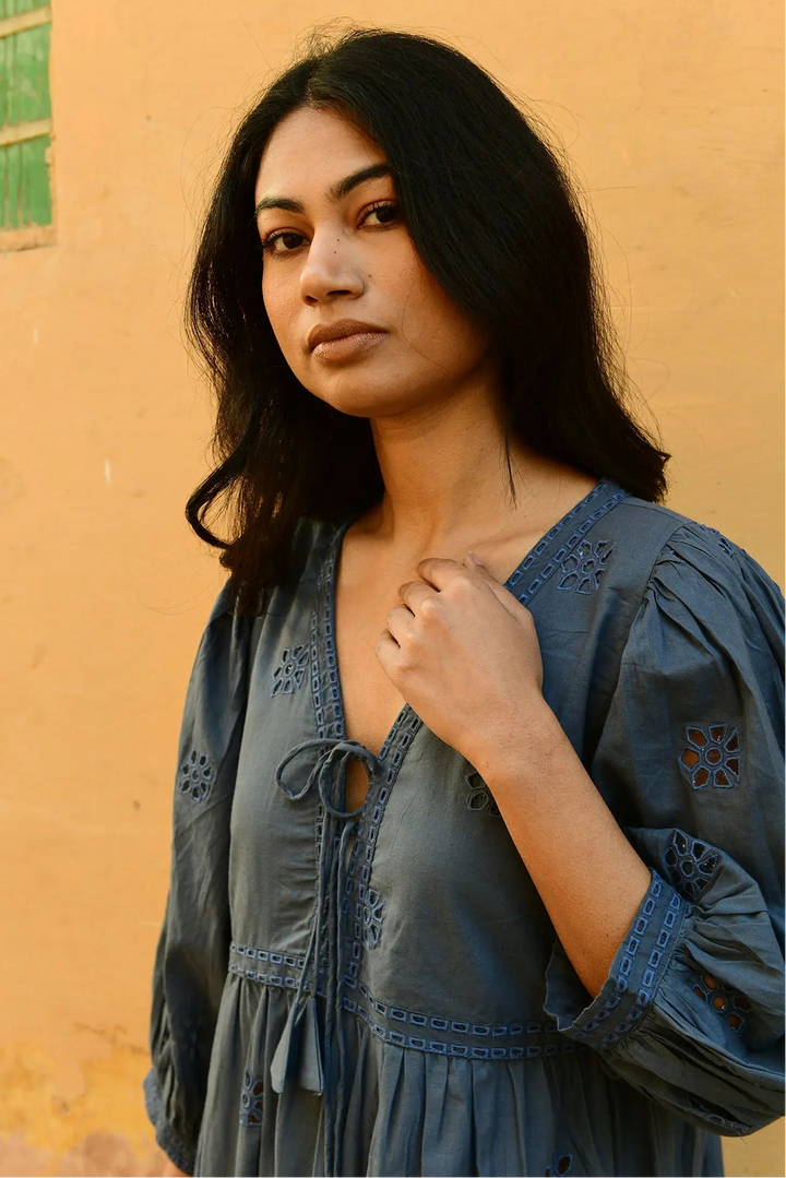Woman wearing a blue dress against a yellow wall