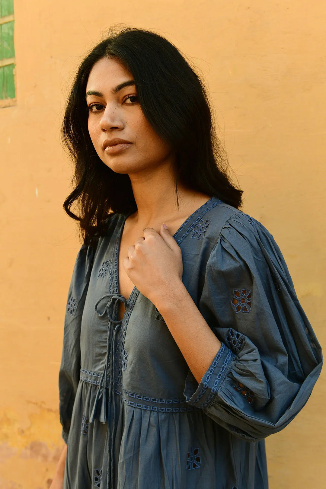 Woman wearing a blue dress against a yellow wall