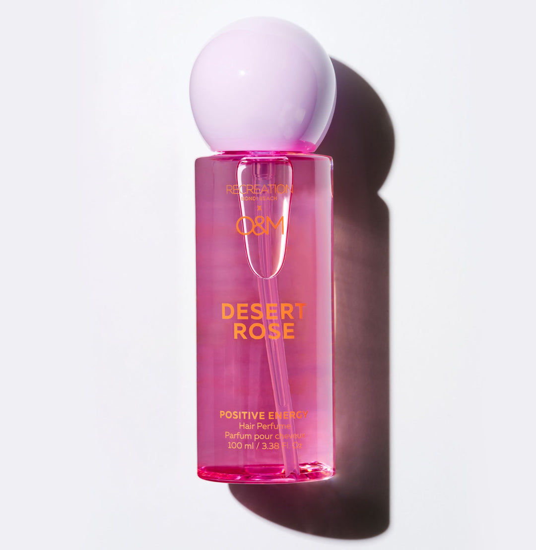 Pink perfume bottle with a white cap on a light gray background