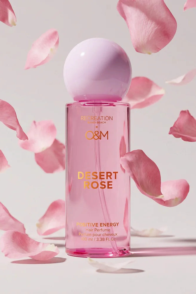 Perfume bottle labeled 'Desert Rose' by O&M with pink petals on a light background