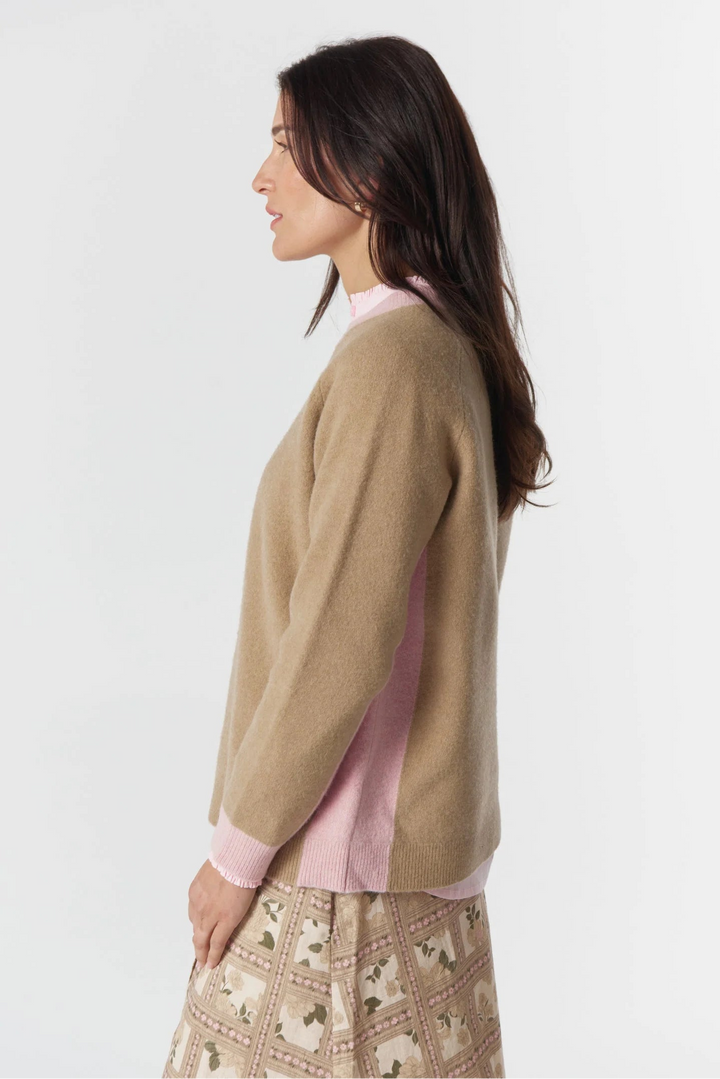Woman wearing a beige sweater over a pink shirt with a white background