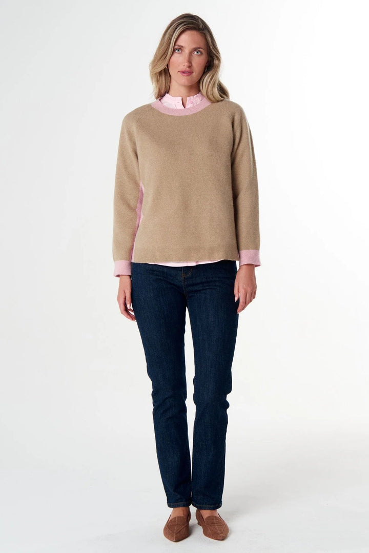 Woman wearing a beige sweater and dark jeans on a white background