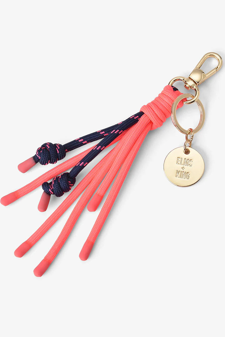 Keychain with pink tassels and a gold tag on a white background