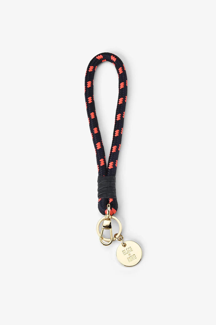 Black and red patterned lanyard with a gold tag on a white background