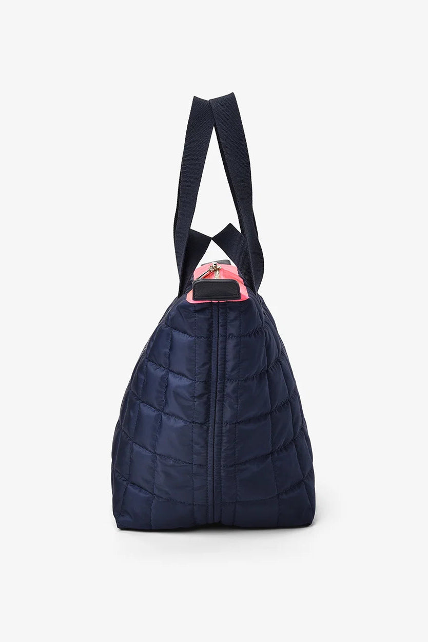 Navy blue quilted handbag with a pink interior on a white background