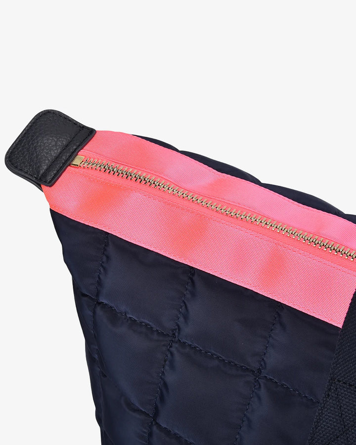 Close-up of a black quilted bag with a pink zipper on a white background