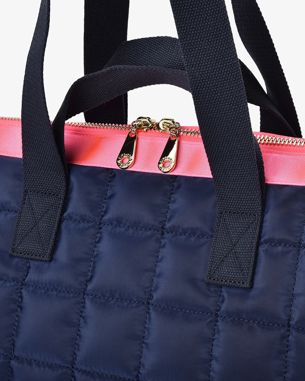 Navy blue quilted bag with a pink zipper and black straps on a white background