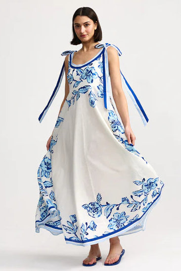 Woman wearing a white dress with blue floral patterns on a white background
