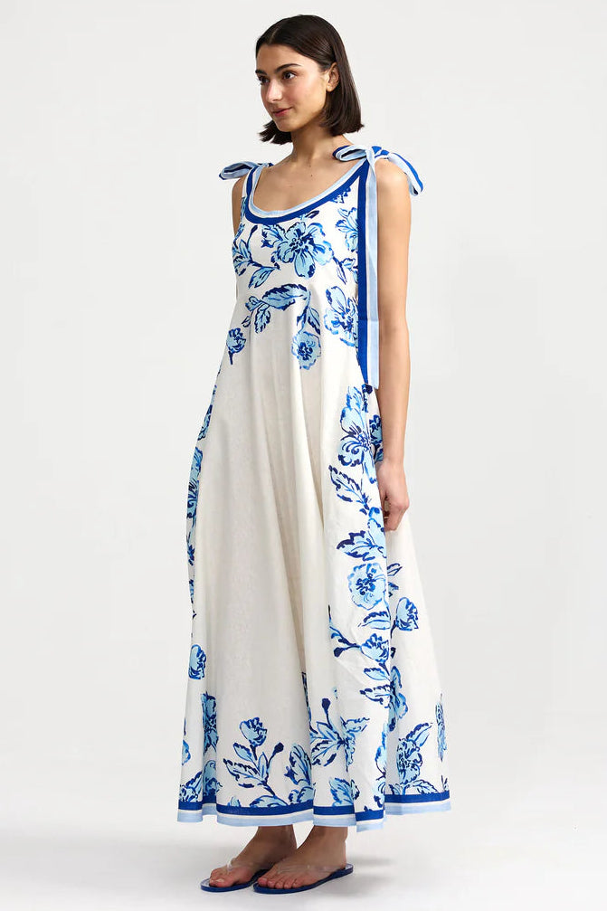 Woman wearing a white dress with blue floral patterns on a white background