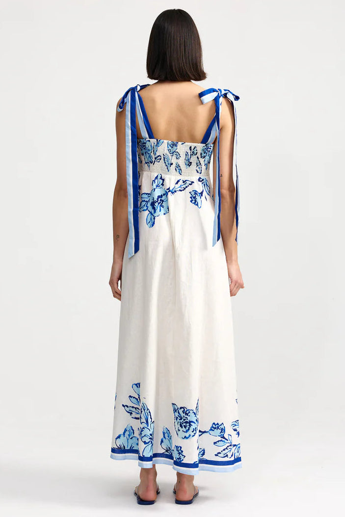 Woman wearing a white dress with blue floral patterns on a white background