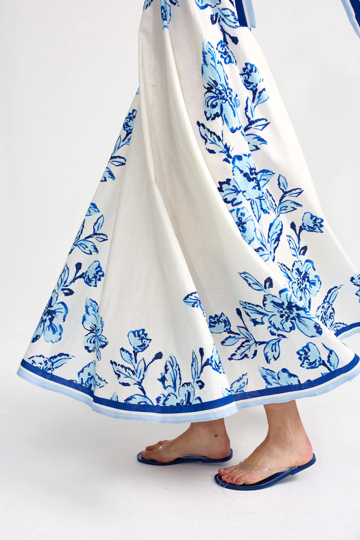 White skirt with blue floral pattern worn by a person on a white background
