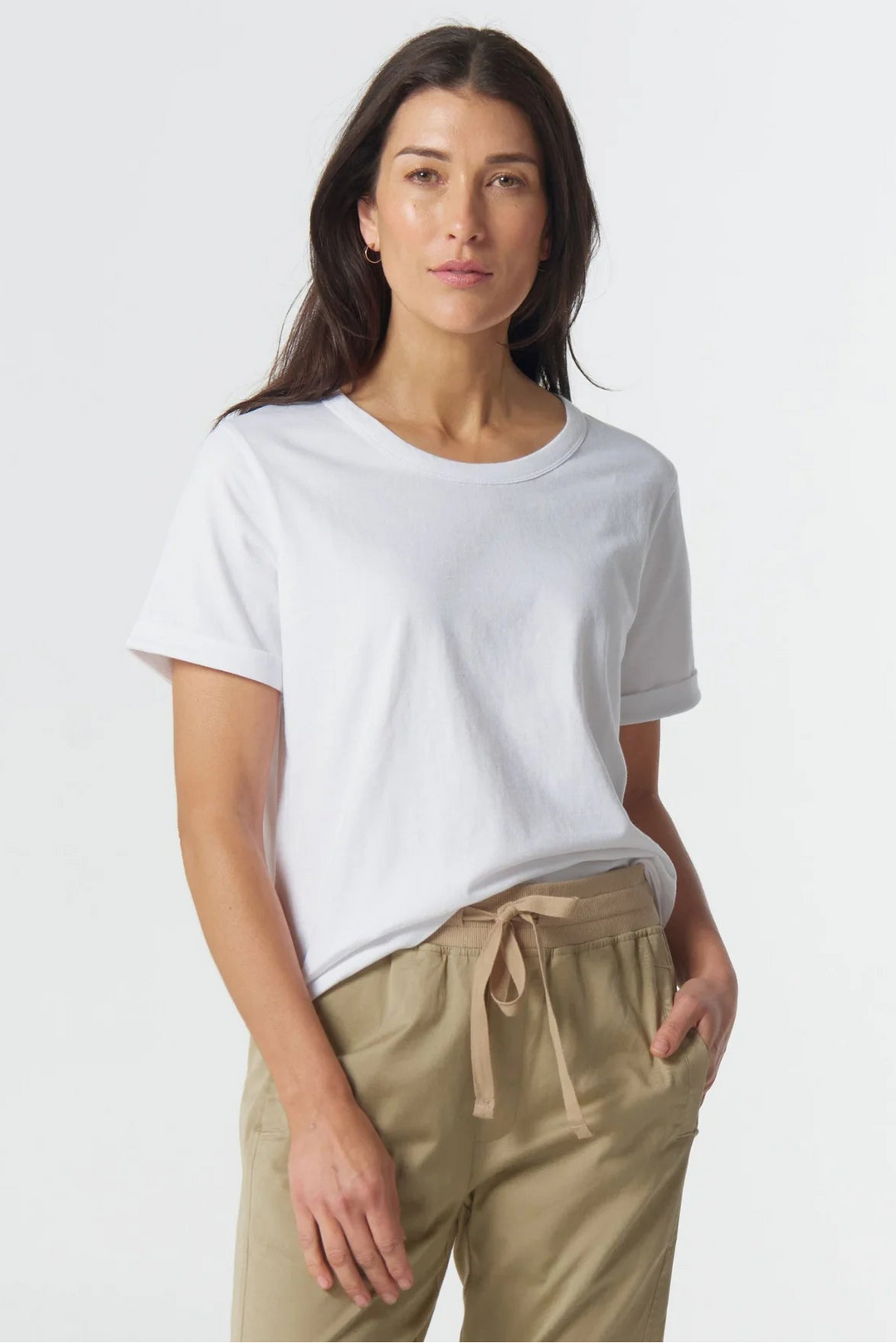 Woman wearing a white t-shirt and beige pants on a plain background