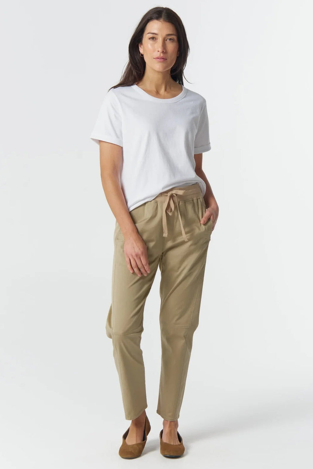 Woman wearing a white t-shirt and beige pants on a white background