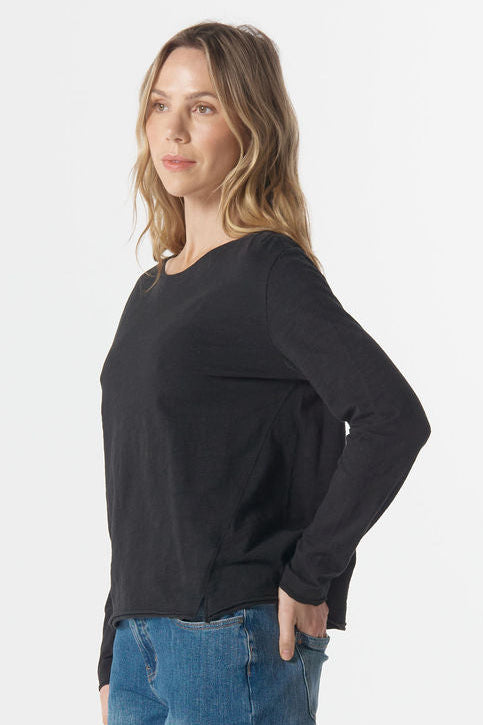 Woman wearing a black sweater and blue jeans on a white background