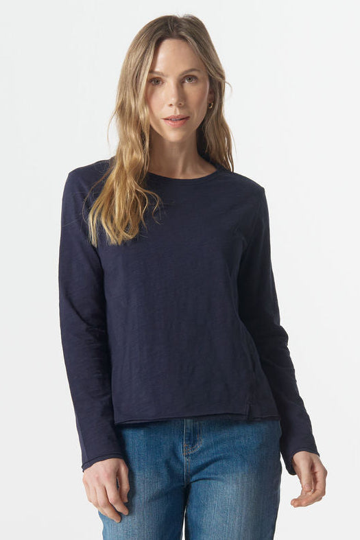 Woman wearing a navy sweater and blue jeans on a white background