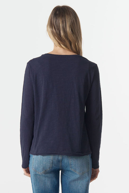 Person wearing a navy long-sleeve shirt and blue jeans on a white background