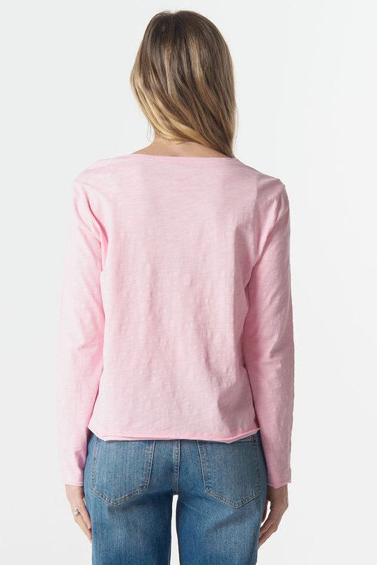 Person wearing a pink long-sleeve shirt and blue jeans on a white background