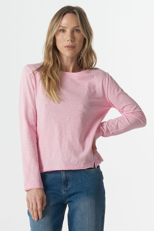 Woman wearing a pink sweater and blue jeans on a white background