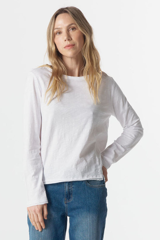 Woman wearing a white long-sleeve shirt and blue jeans on a white background
