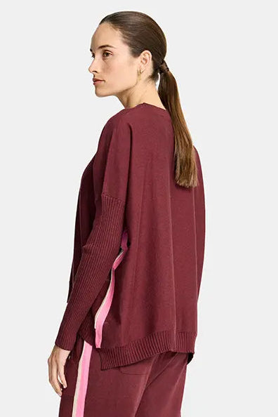 Woman wearing a burgundy tracksuit with pink side stripe on a white background