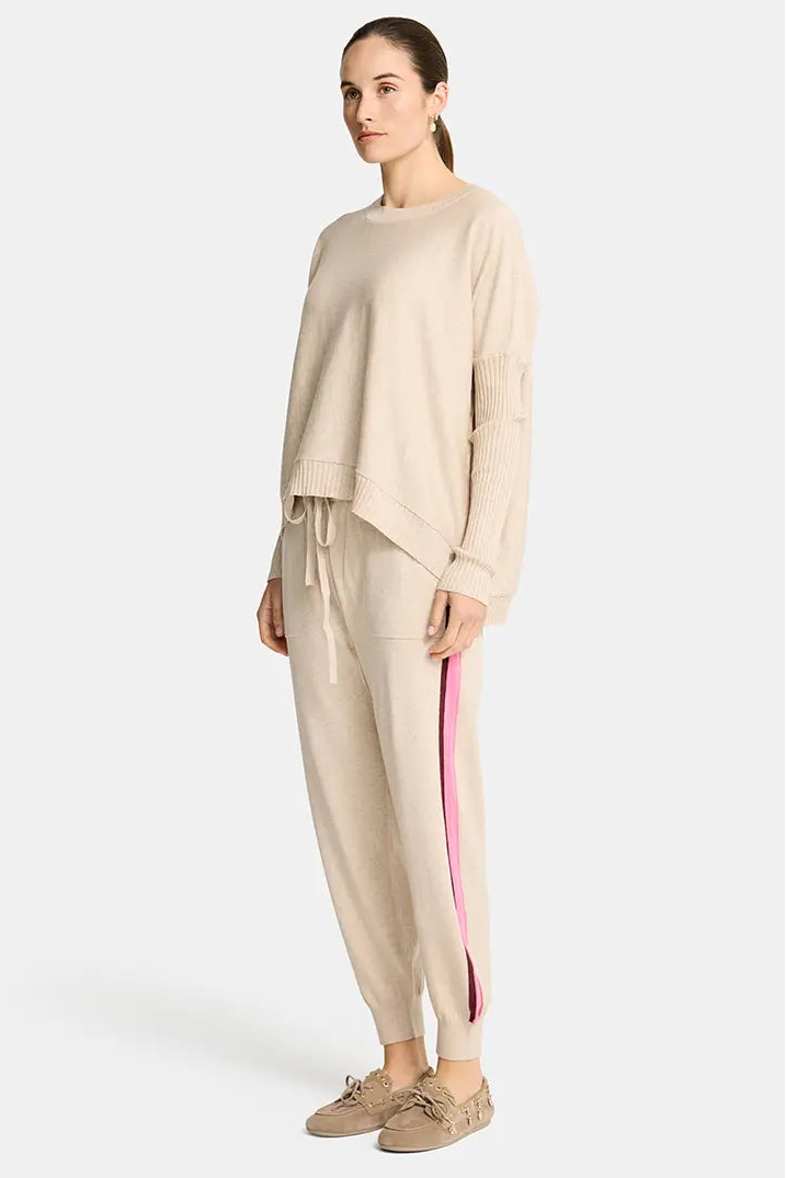 Woman wearing a beige outfit with a pink stripe on a white background