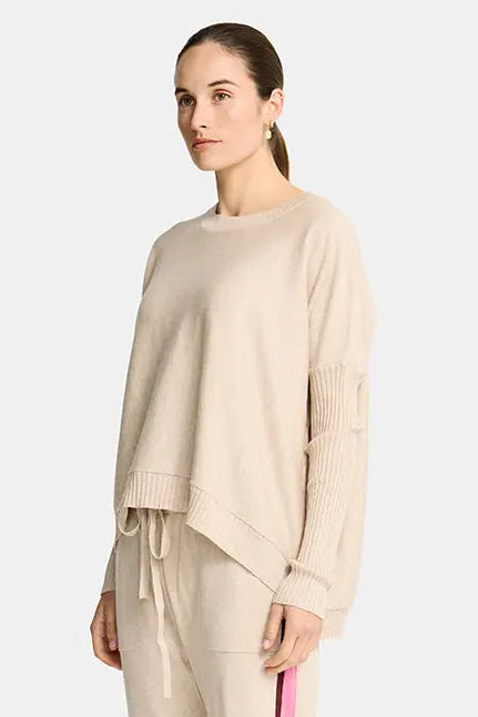 Woman wearing a beige outfit with a pink stripe on a white background