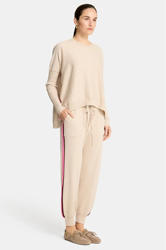 Woman wearing a beige outfit with a red stripe on a white background