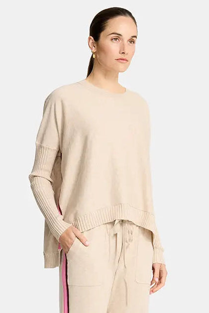 Woman wearing a beige outfit with a red stripe on a white background