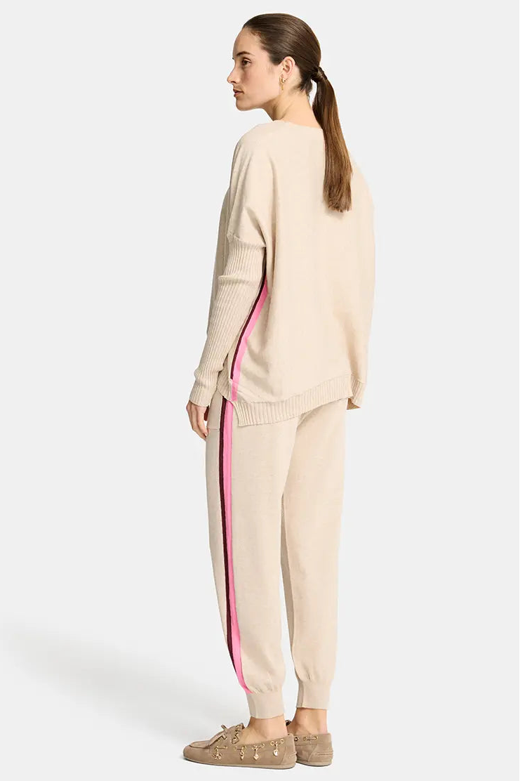 Woman wearing a beige outfit with pink side stripe on a white background