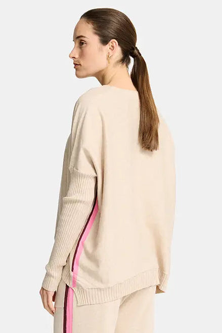 Woman wearing a beige outfit with pink side stripe on a white background