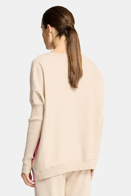 Woman wearing a beige sweater and pants with a pink stripe on a white background