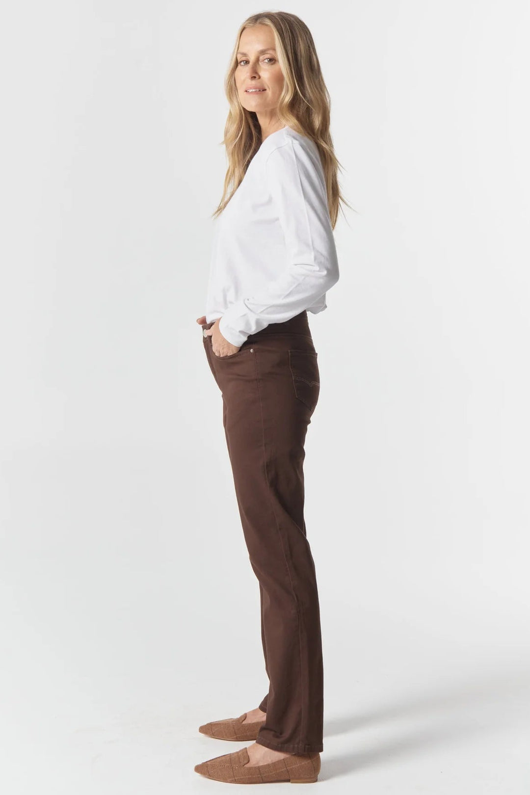 Woman wearing a white blouse and brown pants on a white background