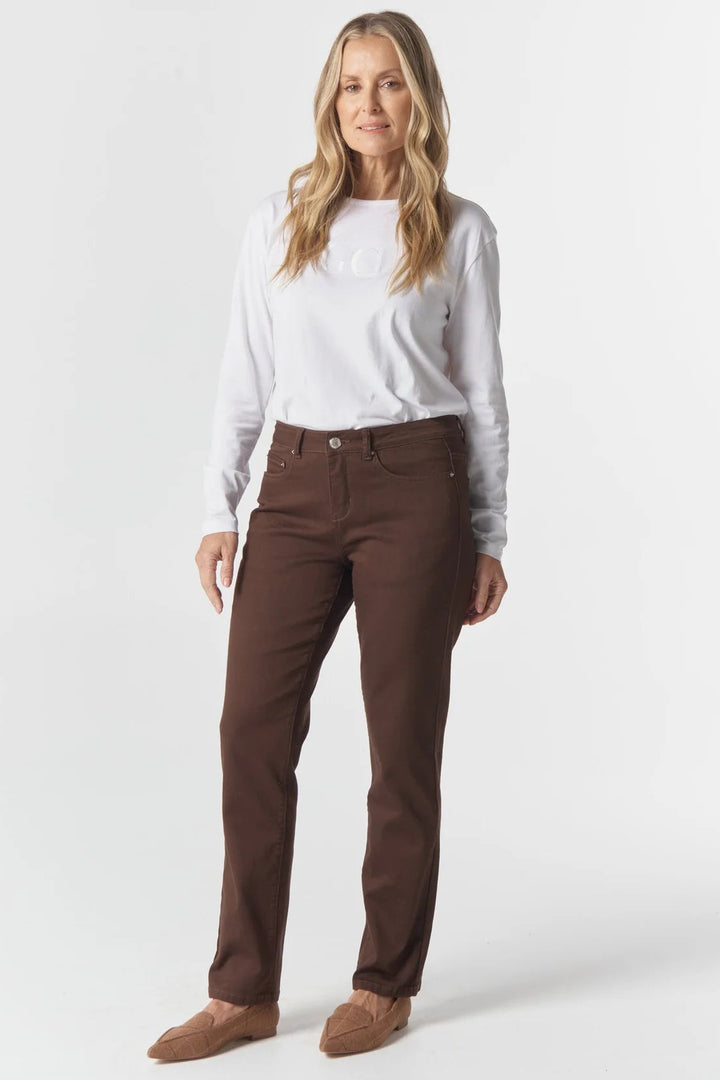 Woman wearing a white long-sleeve shirt and brown pants on a white background