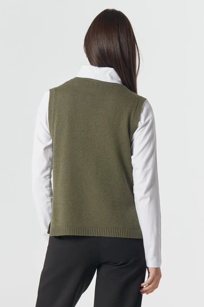 Person wearing a green vest over a white shirt with black pants on a white background