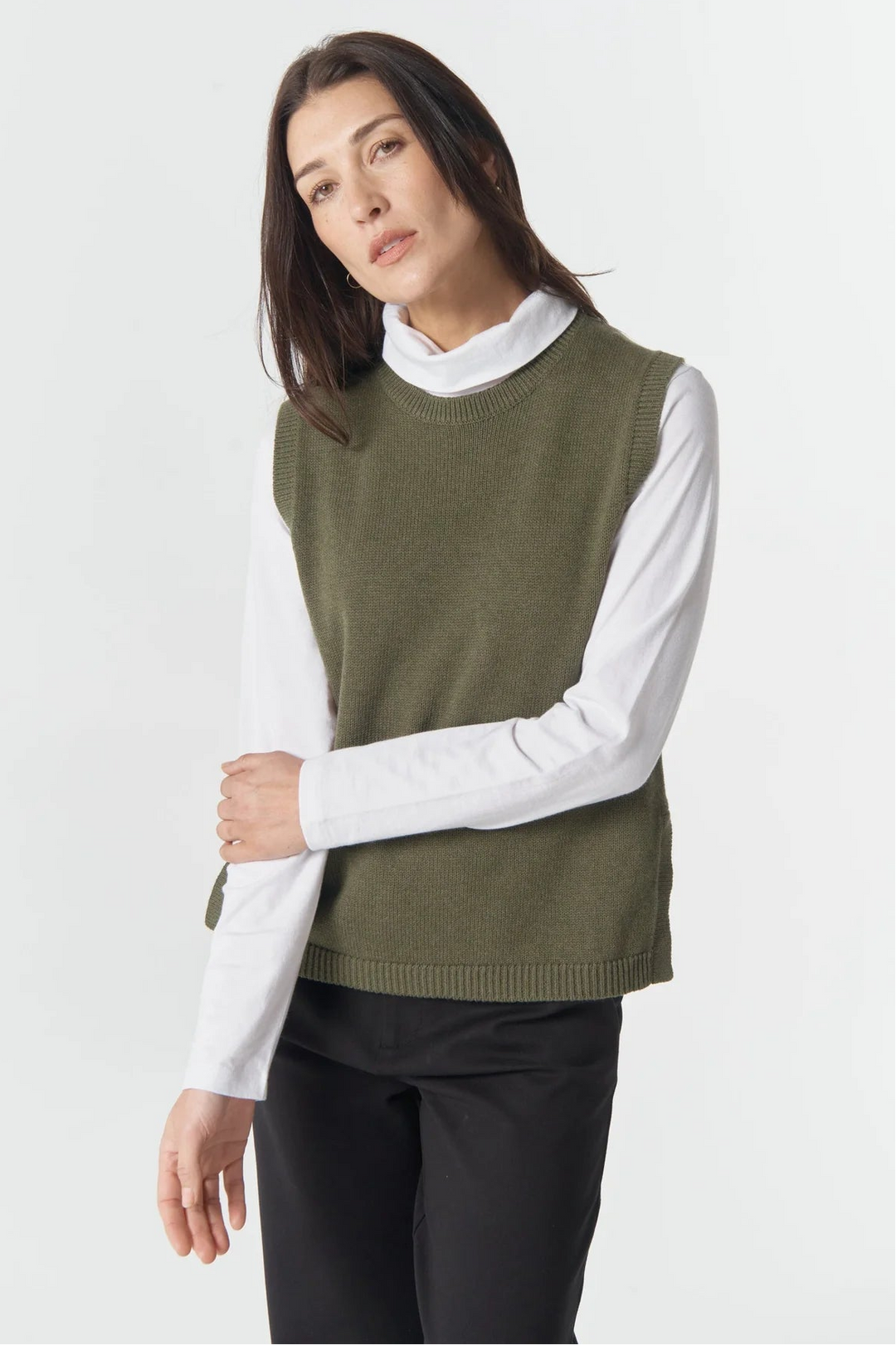 Woman wearing a green sweater vest over a white shirt on a white background