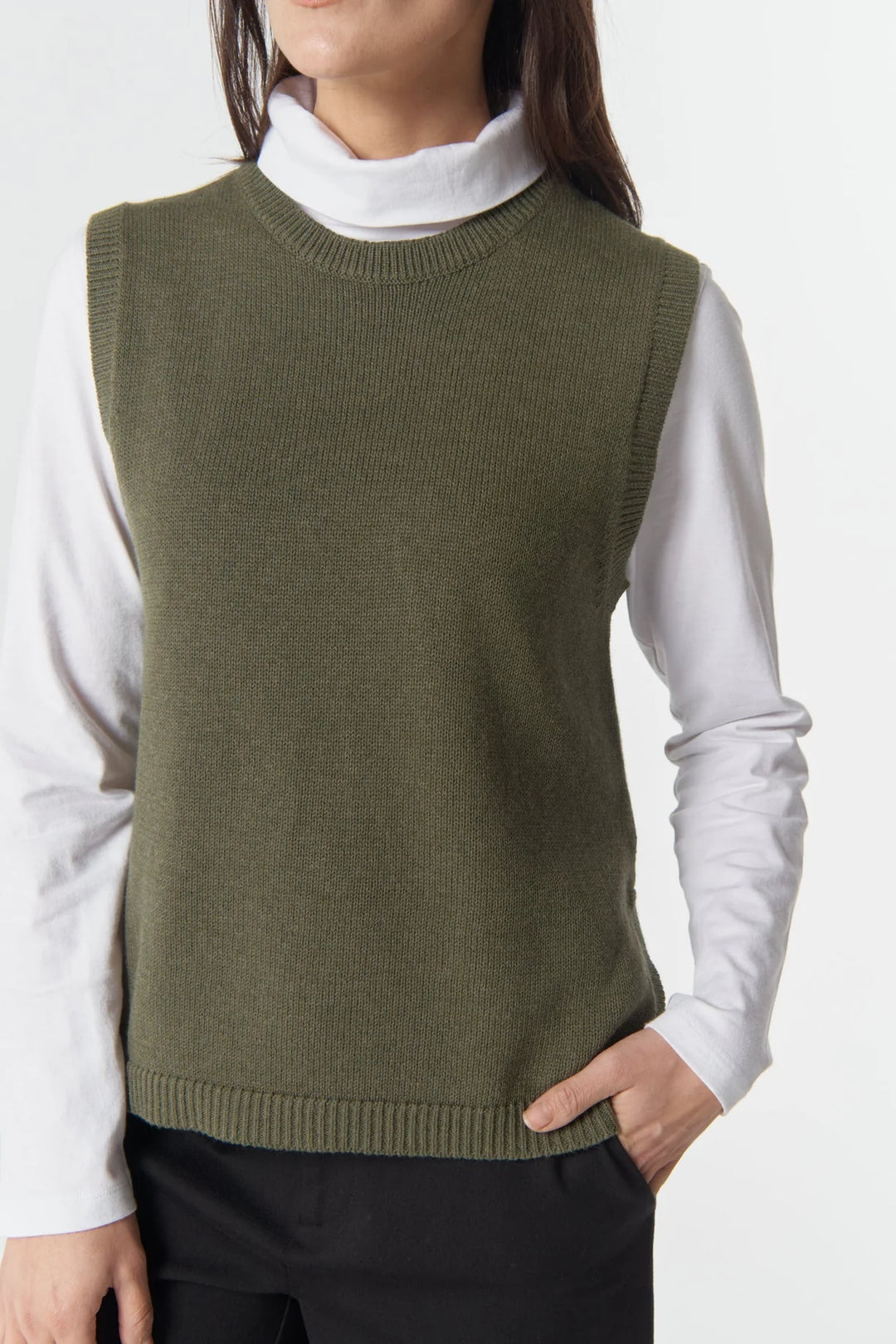 Person wearing a green sweater vest over a white shirt on a white background