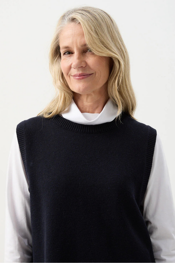 Woman wearing a black vest over a white shirt on a white background