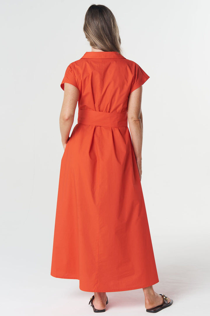 A woman viewed from behind wearing a bright orange-red short-sleeve midi dress with a matching waist tie, paired with black flat sandals, against a plain white studio background.