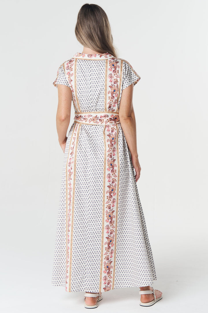 Woman wearing a long, patterned dress with a belt on a white background