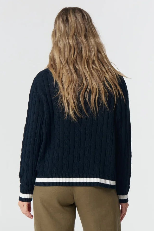 Person wearing a navy sweater and beige pants on a white background