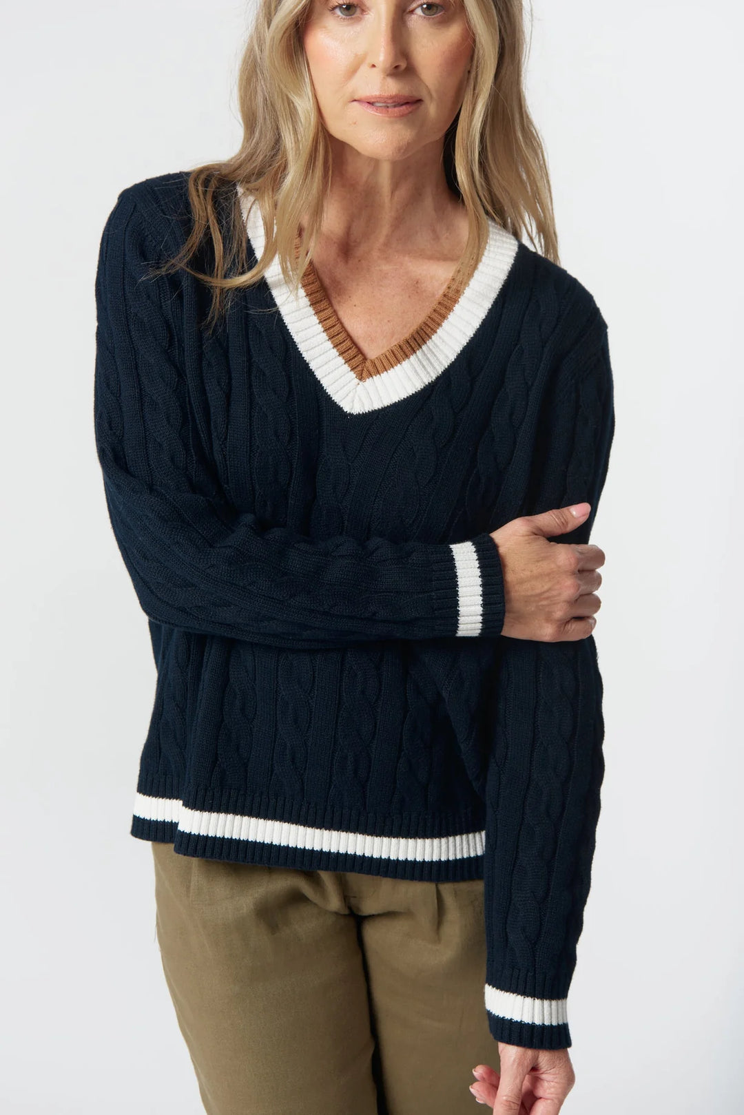Woman wearing a navy sweater with white trim on a white background
