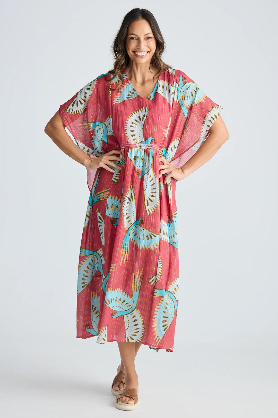 Woman wearing a pink dress with a floral pattern on a white background. Holiday Trading Lorrini Kaftan Red Macaw