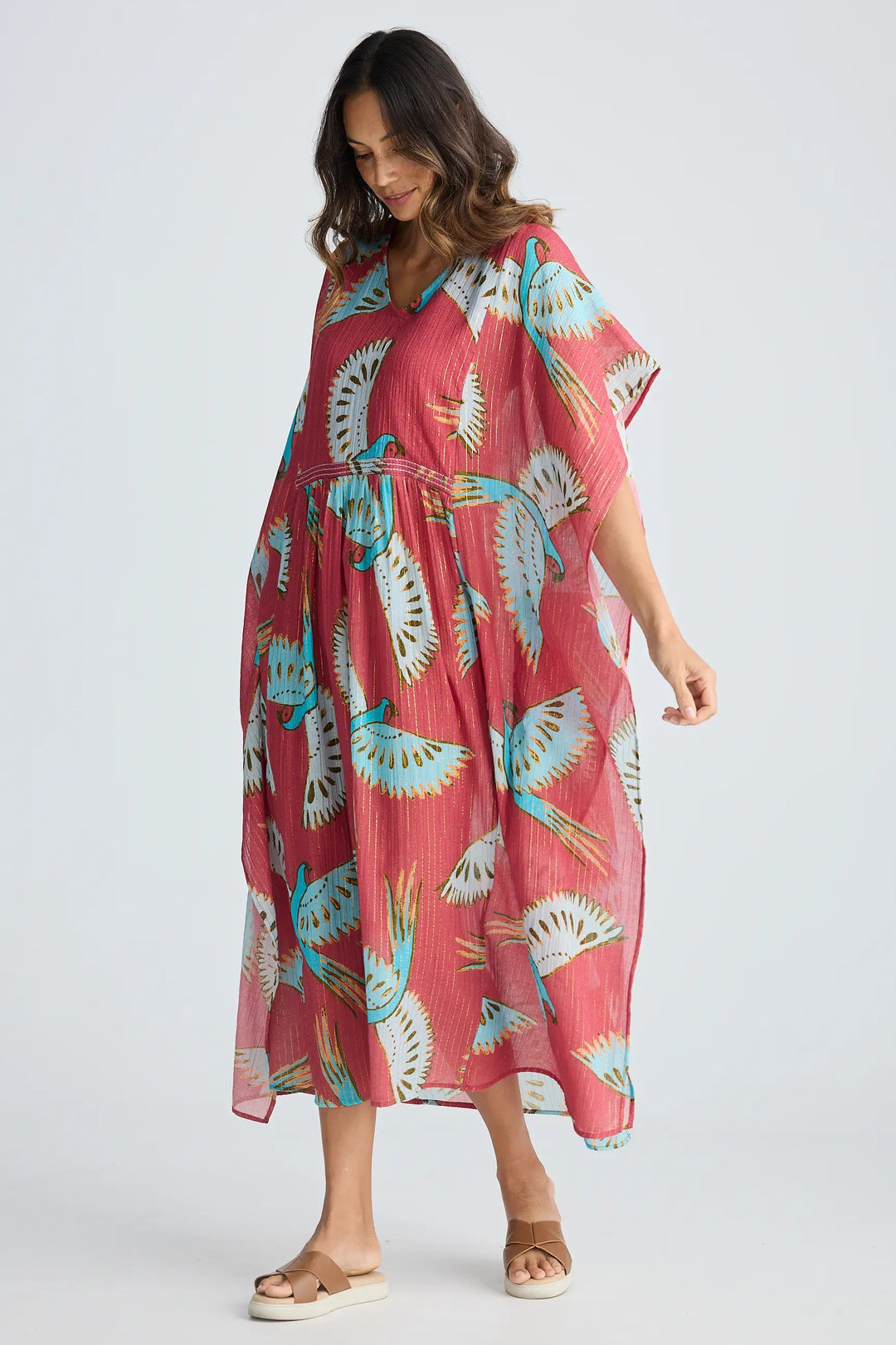 Woman wearing a pink dress with blue floral patterns on a white background. Holiday Trading Lorrini Kaftan Red Macaw