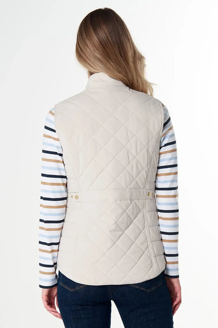 Woman wearing a cream quilted vest over a striped shirt on a white background